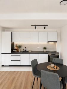 a kitchen with white cabinets and a table and chairs at MangaRenga apartments in Šušanj