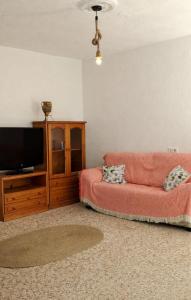 a living room with a red couch and a tv at casa el nacimiento in Igualeja