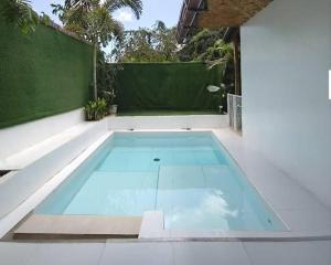 a swimming pool in a backyard with a green fence at Lio Palm Villas in Langi-langiban