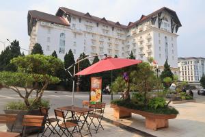a table and chairs with an umbrella in front of a building at Sai Gon Da Lat Premium in Da Lat