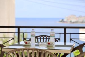 a table with two water bottles and cups on a balcony at Unico ApartHotel in Sarandë