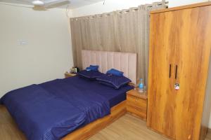 a bedroom with a blue bed and a wooden cabinet at FabHotel Aqua Pearl Inn in Navi Mumbai