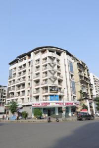 a large white building with cars parked in front of it at FabHotel Aqua Pearl Inn in Navi Mumbai