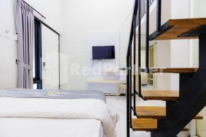 a bedroom with a bed and a staircase with a tv at Tree Homestay Mitra RedDoorz in Kasri