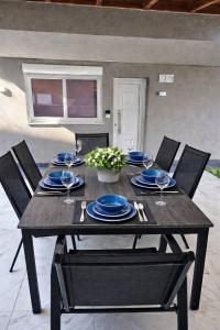 a wooden table with blue plates and wine glasses at BAS Garden Apartment Paralia in Paralia Katerinis