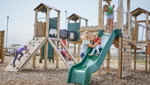 a group of children playing on a playground at Beach Retreats, Romney Sands, Parkdean Resorts in Greatstone