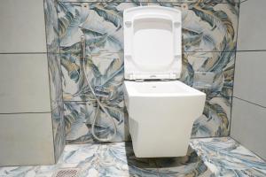 a white toilet in a bathroom with ailed wall at Vi Grand inn in Satyamangalam