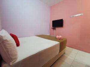 a bedroom with a bed with pink walls and a tv at My Seven Day Inn in Masai