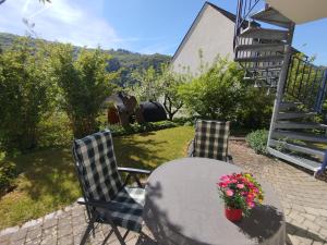 a table and two chairs with flowers on a patio at Ferienwohnung Brigatt in Klotten