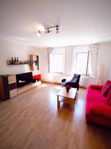 a living room with a red couch and a coffee table at Ferienwohnung Brigatt in Klotten +11 photos
