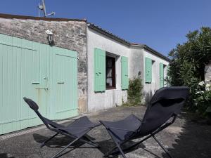two chairs sitting in front of a building with green doors at Maisonnette au centre de St Pierre in Saint-Pierre-dʼOléron