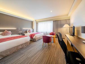 a hotel room with two beds and a desk at KKR Hotel Hakata in Fukuoka +19 photos