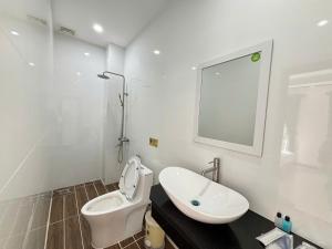 a white bathroom with a toilet and a sink at Khách sạn Vân Nhi 2 in Bạc Liêu