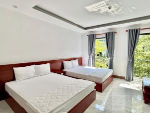 a bedroom with two beds and a balcony at Khách sạn Vân Nhi 2 in Bạc Liêu