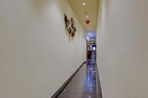 a hallway with a white wall and a tile floor at Hotel O Golden Suites in Turambhe