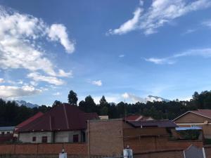 a group of houses with a blue sky and clouds at Bella Famiglia in Ruhengeri