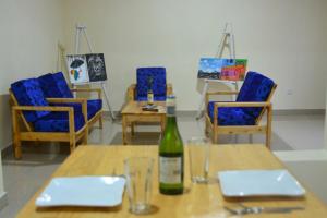 a table with a bottle of wine and blue chairs at Bella Famiglia in Ruhengeri