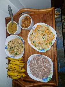a wooden tray with plates of food and bananas on it at TRINCO VISTARA GUEST House APARTMENT in Trincomalee