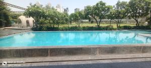 a large blue swimming pool in a park at Udman Hotel Greater Noida in Greater Noida