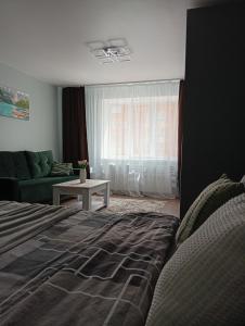 a bedroom with a bed and a couch and a window at Dolce Vita in Ternopil