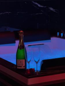 a bottle of wine and two glasses on a table at Hollywood Spa Jacuzzi - Cinéma in Château-Thierry