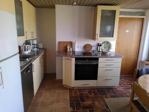eine Küche mit weißen Schränken und Fliesenboden in der Unterkunft Zimmer 13 in Gomadingen