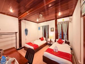 a room with two beds and a table in it at Villa Ouis NamKhan River View in Luang Prabang