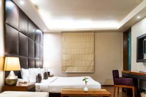 a hotel room with a bed and a desk at Udman Hotel Panchshila Park in New Delhi