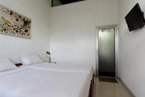 a white room with two beds and a tv at Nest Hotel Jogja in Seturan