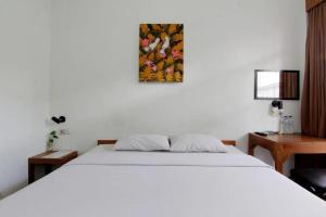 a bedroom with a white bed and a desk at Nest Hotel Jogja in Seturan