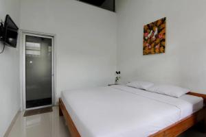 a white bedroom with a bed and a window at Nest Hotel Jogja in Seturan