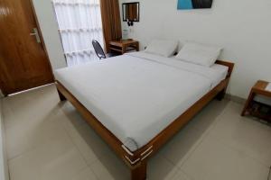 a bedroom with a bed with white sheets and a window at Nest Hotel Jogja in Seturan