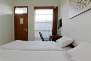a bedroom with two beds and a desk and a window at Nest Hotel Jogja in Seturan +7 photos