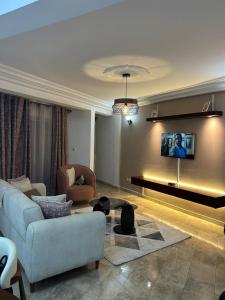 a living room with a couch and a tv on a wall at Appartement cozy Bonamoussadi, WIFI & Goupe électrogène in Douala