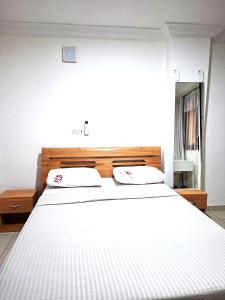 a white bed with two pillows on top of it at Monica Place in Abidjan