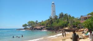 a lighthouse on a beach with people in the water at Lighthouse Peacock Villa in Dondra West
