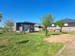 a house in a yard with trees and grass at Tiny house het Polderhuisje in Streefkerk +12 photos