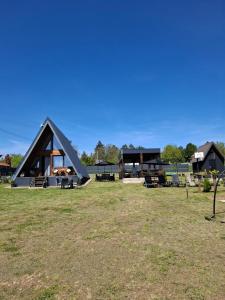 a frame house with a black roof in a field at Vikendica na Avali in Donja Ralja