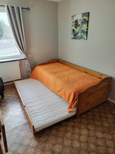 a bedroom with a bed with an orange sheet at Bettan in Bruzaholm