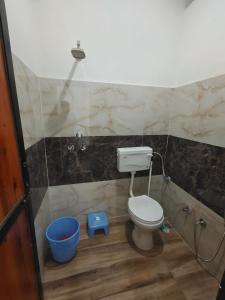 a bathroom with a toilet and a bucket at Anmol Hotel And Restaurant in Chandausi