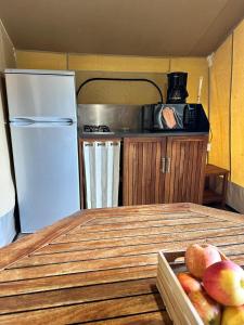 a kitchen with a refrigerator and a table with a tray of fruit at Camping Le Sans Souci in Fresnay-sur-Sarthe +8 photos