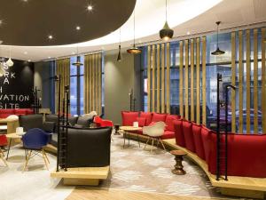 a waiting room with red chairs and tables and windows at ibis Yerevan Center in Yerevan