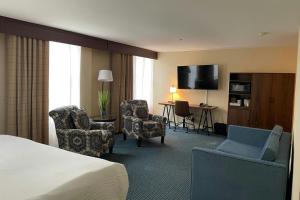 a hotel room with a bed and chairs and a television at Four Points by Sheraton Wakefield Boston Hotel & Conference Center in Wakefield