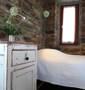a bedroom with a bed and a dresser with flowers on it at Tinos Ecolodge in Tinos