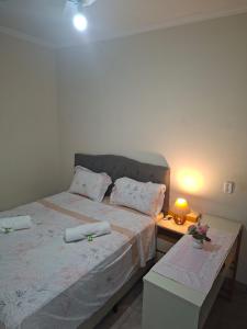 a bedroom with a bed and a table with a lamp at Hosting Altos da cidade perto de tudo in Bauru
