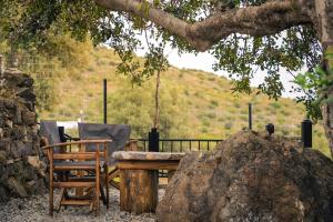 a wooden table and two chairs under a tree at Vrachos Nature Lodges PRINOS 3, Private pool in Agia Galini