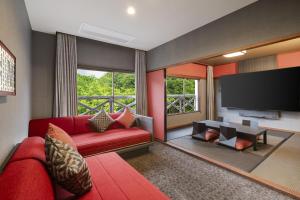 a living room with a red couch and a flat screen tv at Kamenoi Hotel Aso Park Resort in Aso