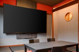 a large flat screen tv on a wall with a table at Kamenoi Hotel Aso Park Resort in Aso