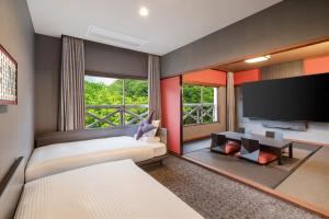 a hotel room with two beds and a flat screen tv at Kamenoi Hotel Aso Park Resort in Aso