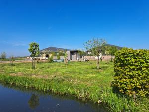 a river with a house in the background at Tiny house het Polderhuisje in Streefkerk